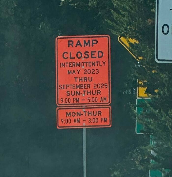 Orange road sign showing ramp closed intermittently with confusing schedule details causing driver uncertainty.
