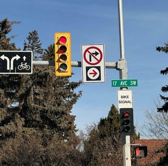 Confusing road signs including no right turn, bike signal, and conflicting traffic lights at 17 Ave SW intersection.