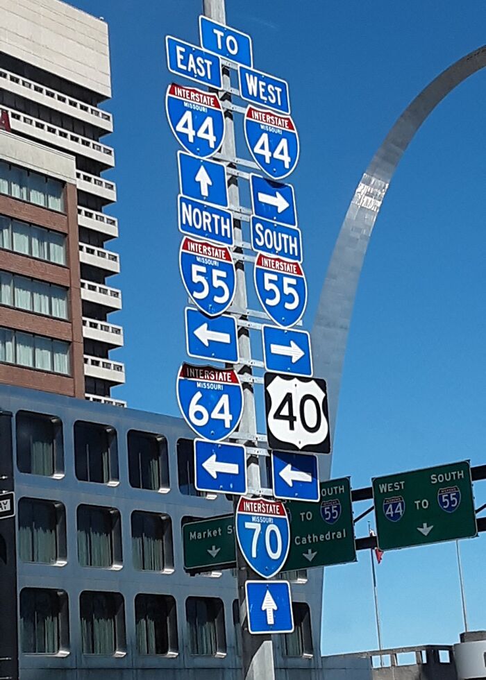 Confusing road signs cluster with multiple interstate directions and arrows, making navigation difficult for drivers.