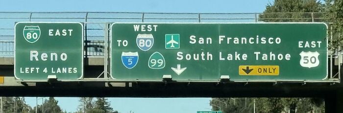 Confusing road signs showing multiple highway directions to Reno, San Francisco, and South Lake Tahoe with overlapping routes.