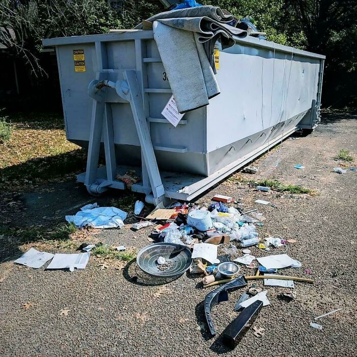 Large dumpster with trash scattered on the ground around it, showing a mildly infuriating mess that tests patience.