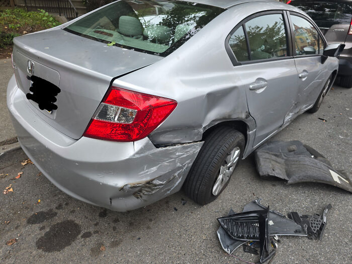 Silver Honda sedan with severe rear and side damage, showing broken car parts on the ground, illustrating mildly infuriating patience tests.