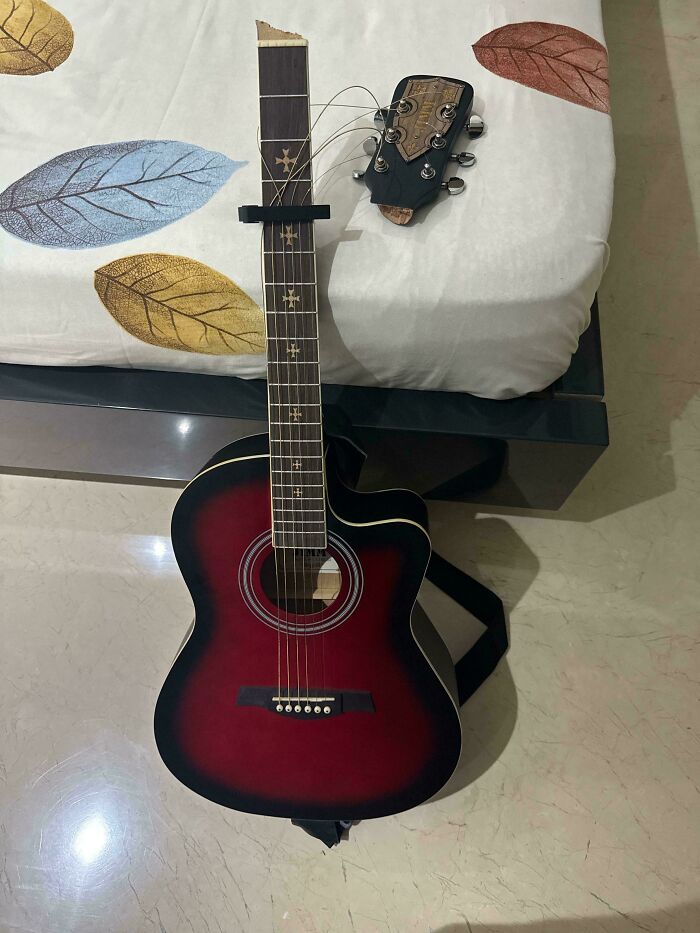 Broken guitar with missing neck head causing frustration, a mildly infuriating thing testing people's patience at home.