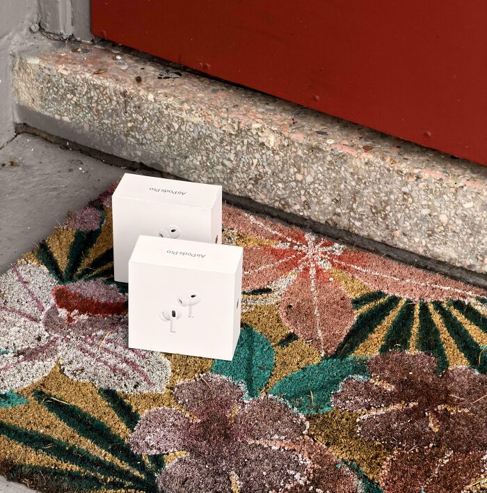 Two mismatched AirPods Pro boxes placed on a colorful floral doormat, a mildly infuriating patience test.