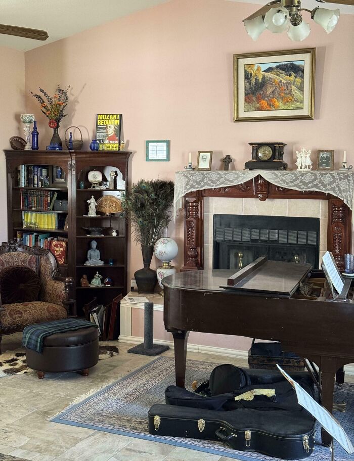 Cat blending seamlessly into a cozy living room with a piano, bookshelf, and vintage decor near the fireplace.