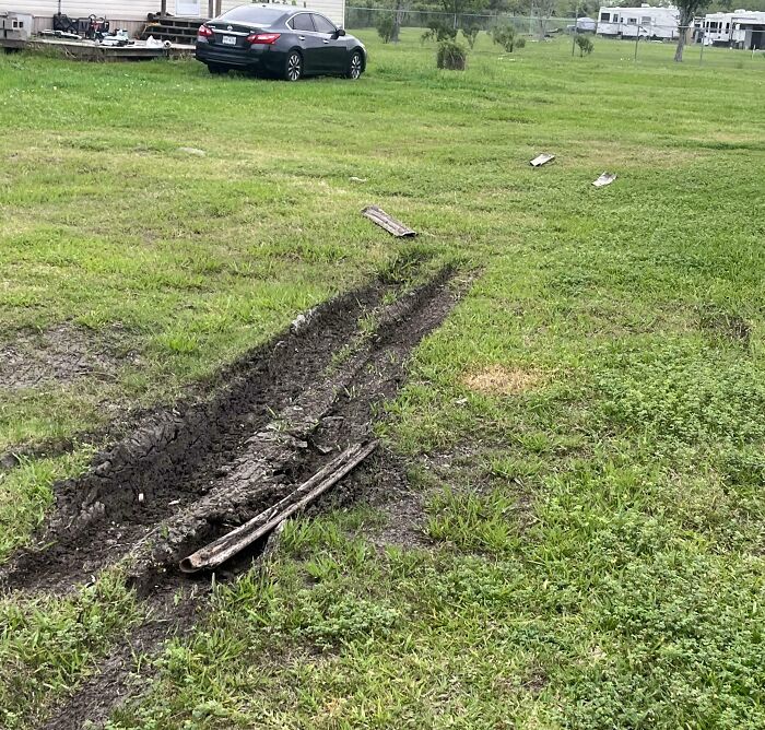 Muddy tire tracks left deep ruts across a grassy field, showcasing a mildly infuriating moment testing patience.