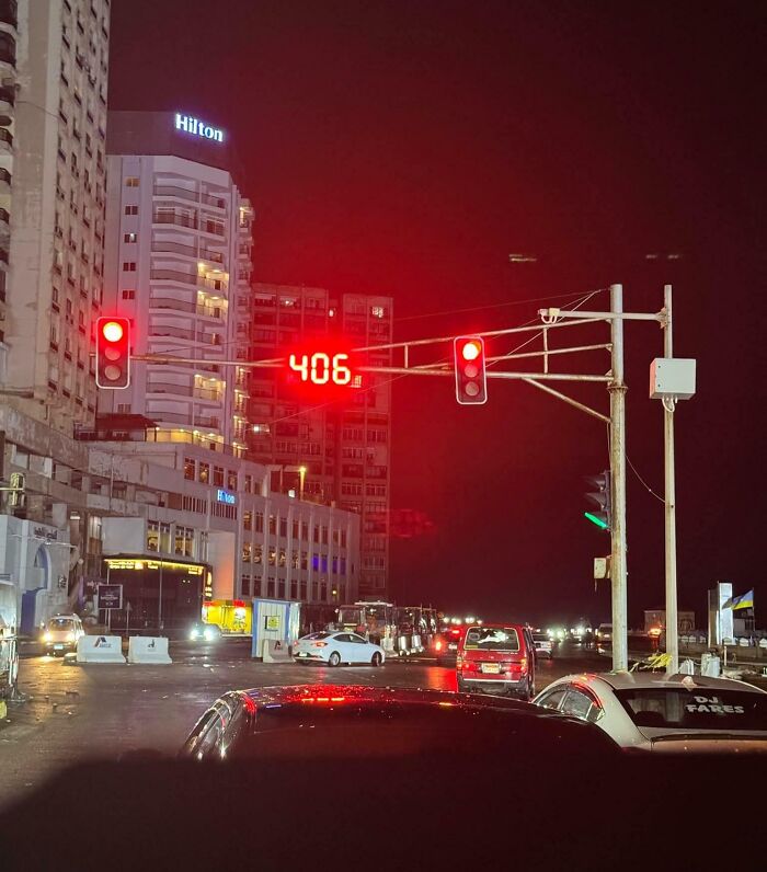 Traffic light showing an excessively long red countdown timer testing people’s patience at night in a city intersection.