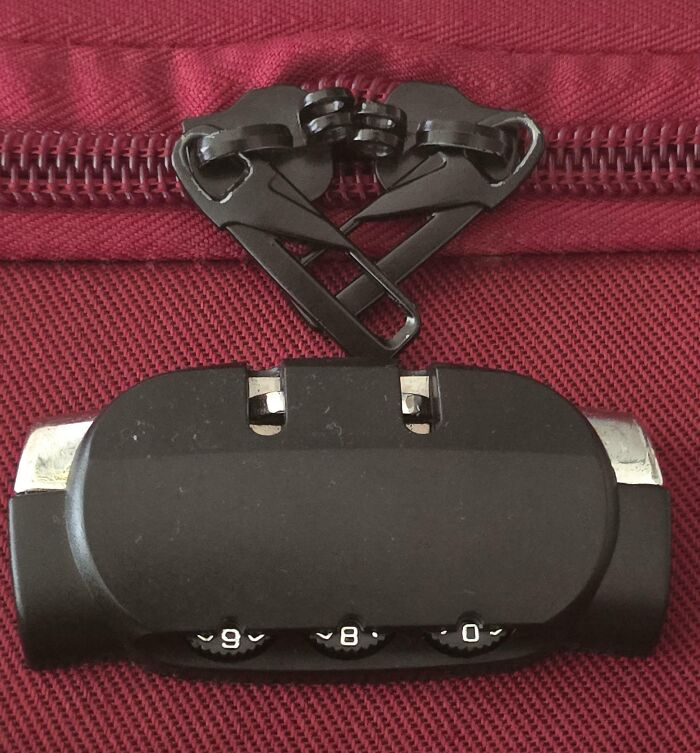 Close-up of zipper on red luggage where two slider pulls are locked together, showing a mildly infuriating design flaw testing patience.