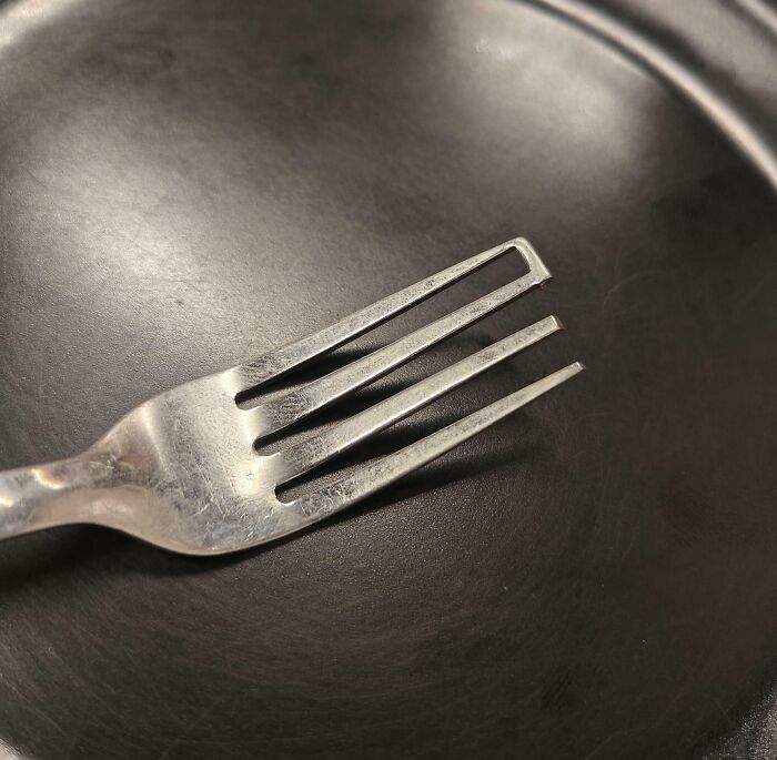 Fork with a broken tine resting on a black plate, illustrating mildly infuriating things that tested people’s patience.