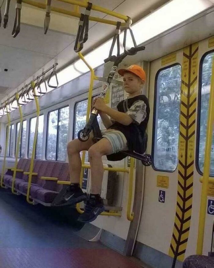 Boy on a scooter cleverly hanging from a subway handlebar, showcasing kids outsmarting grown-ups in a creative way.