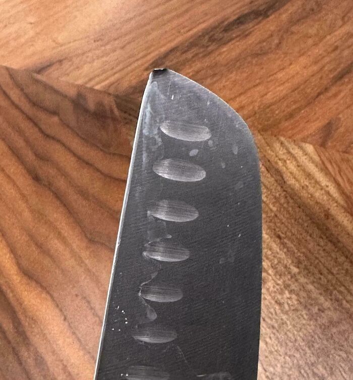 Close-up of a knife with a bent, damaged tip on a wooden surface, showing a mildly infuriating flaw testing patience.