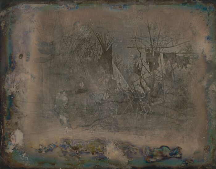 Early faded photo showing Native American teepees and trees, a rare image from the time when photography was new.