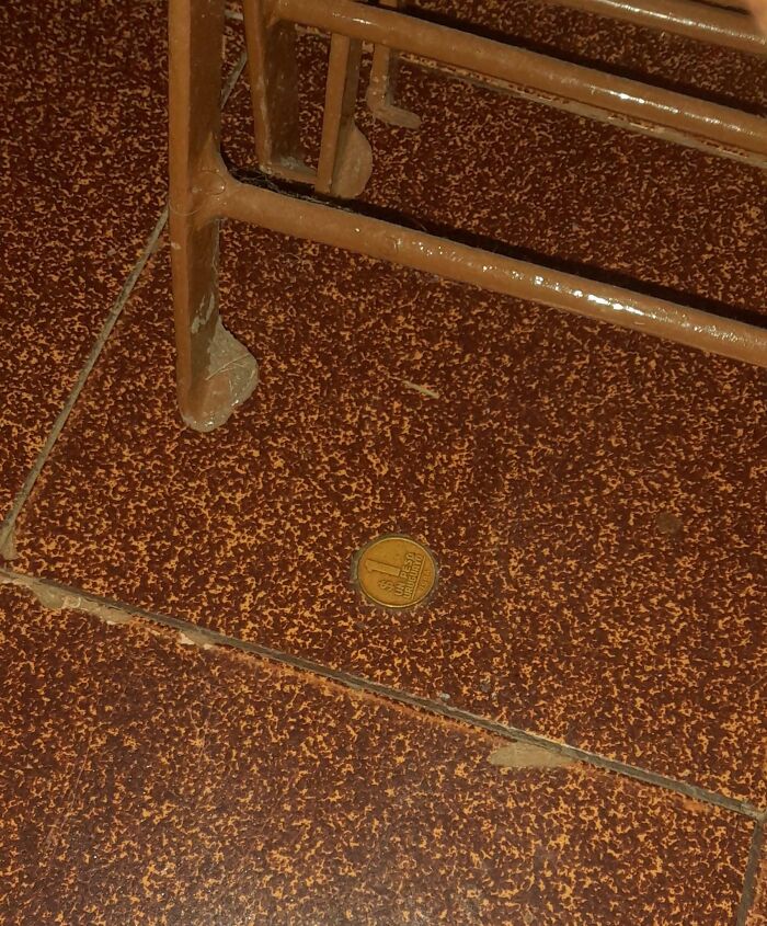 One coin stuck under a chair leg on old brown tiled floor, mildly infuriating patience tester.