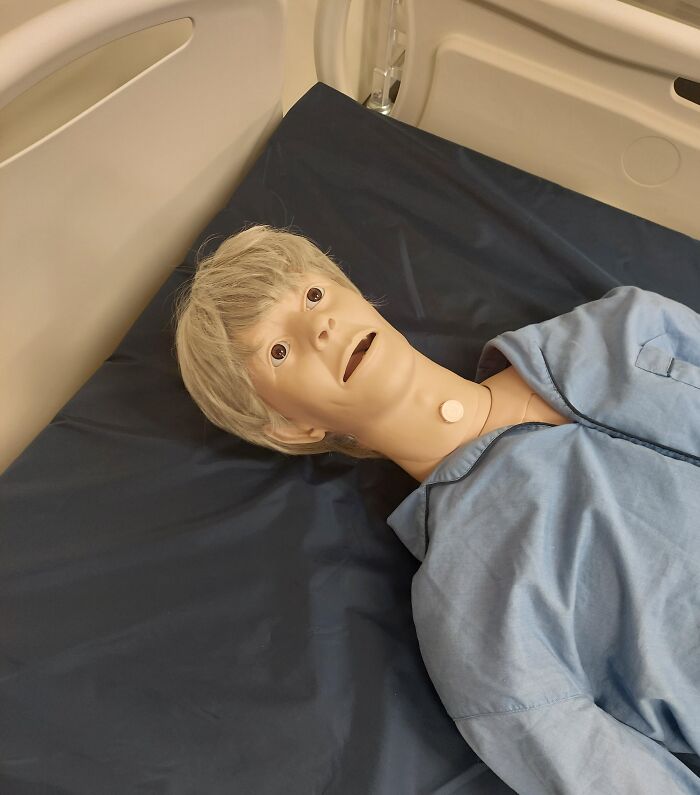 Hospital mannequin with wide eyes lying on a bed, highlighting creepy and unsettling jobs that should pay more.
