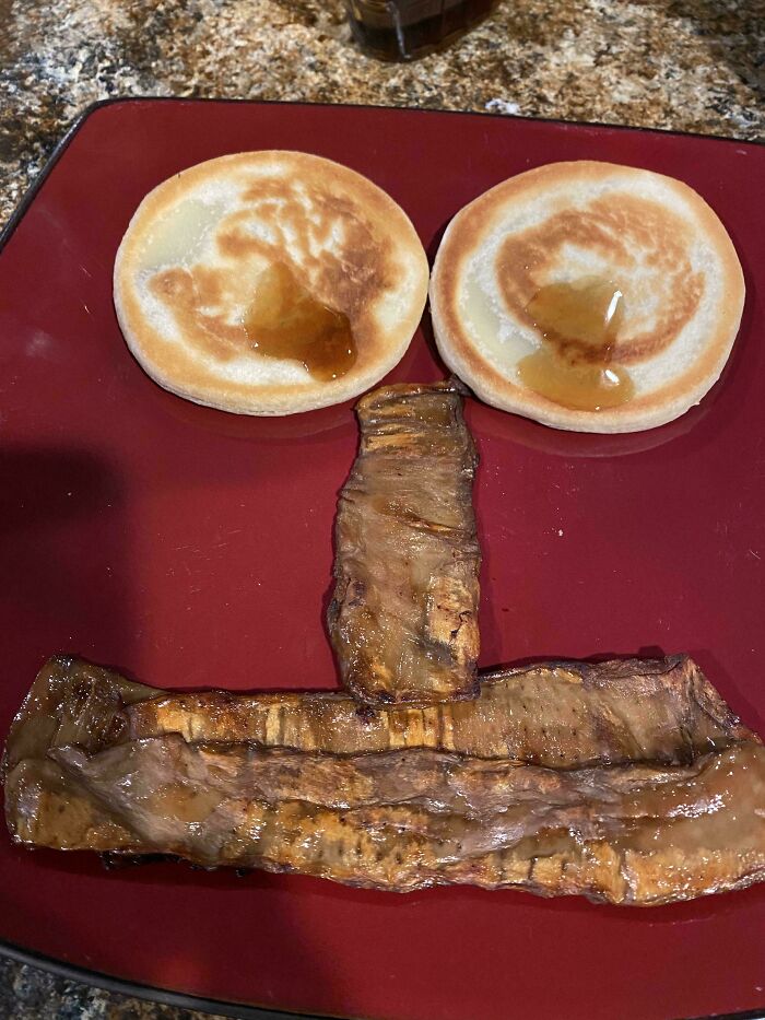 Plates with pancakes and syrup, grilled meat arranged to resemble a face in cursed and disgusting food pictures.