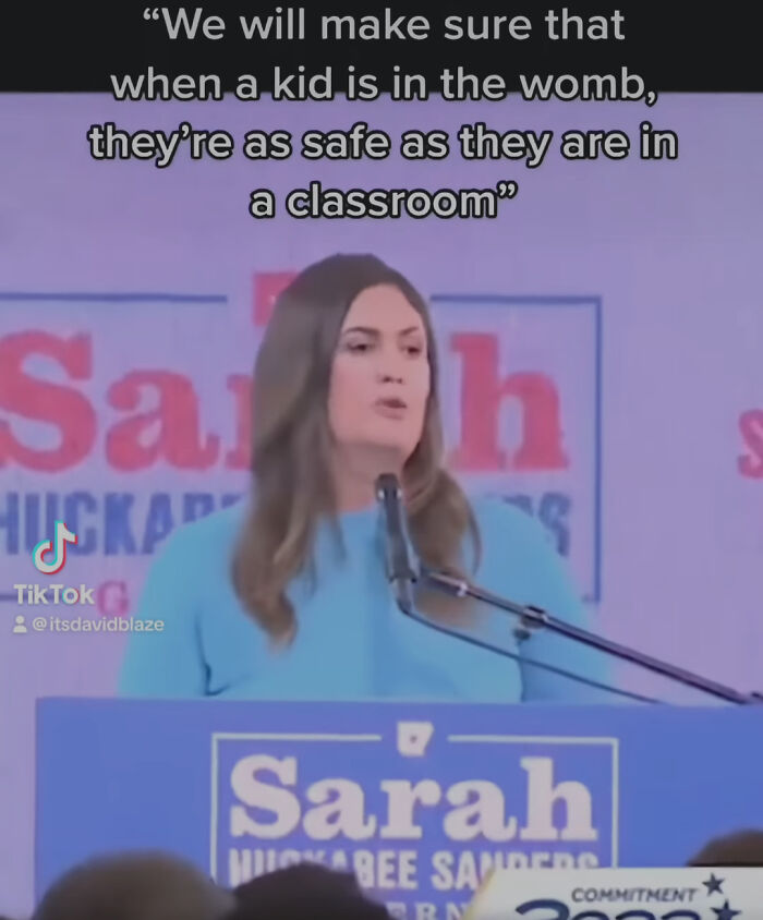 Woman giving a speech with accidental comedy quote about safety of kids in the womb compared to classrooms.