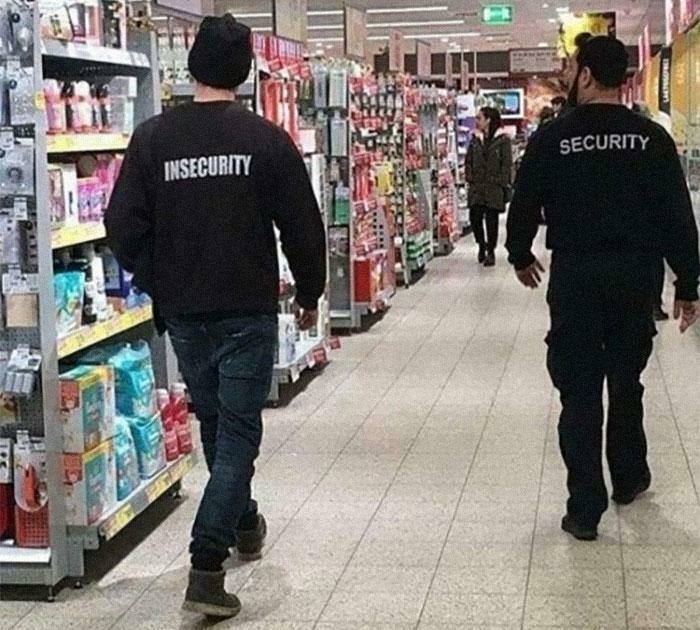 Two men walking in a store aisle wearing jackets labeled insecurity and security, creating accidental comedy.
