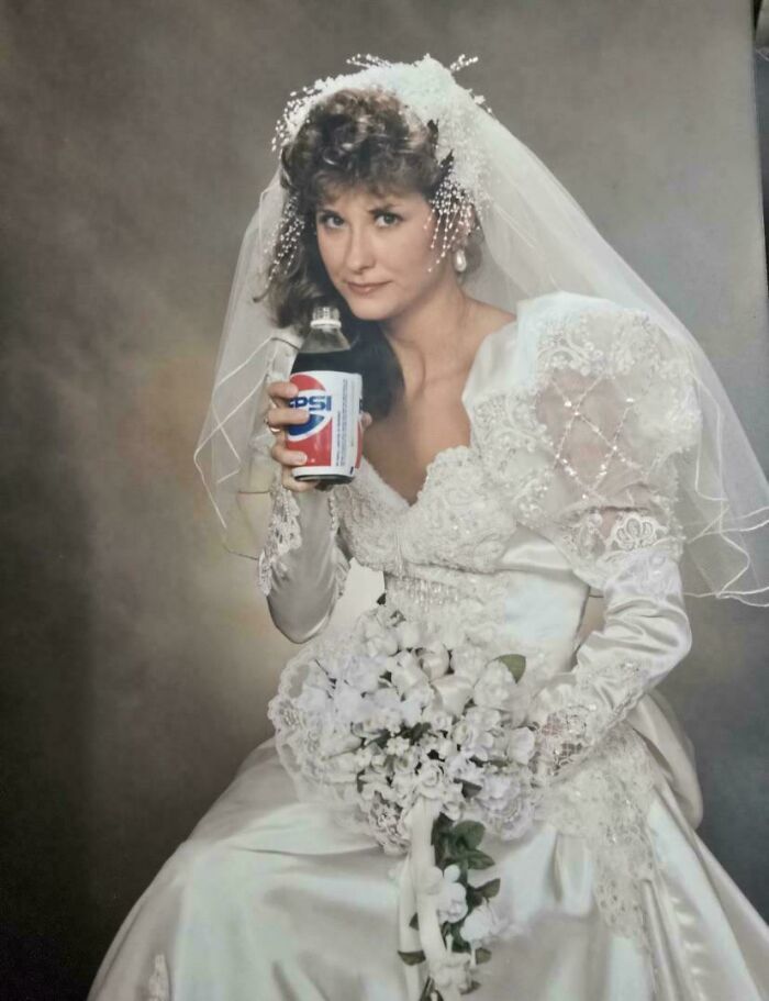 Bride in a vintage 1980s wedding dress holding a Pepsi can, showcasing wild and wonderful 1980s fashion and style.