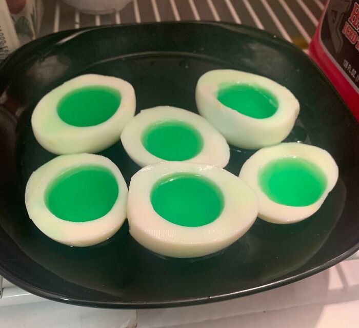 Six white and green gelatin molds on a black plate, a cursed and disgusting picture of food that might disgust viewers.