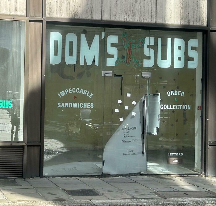 Storefront with broken glass and sandwich shop signage creating accidental comedy in a seemingly harmless funny scene