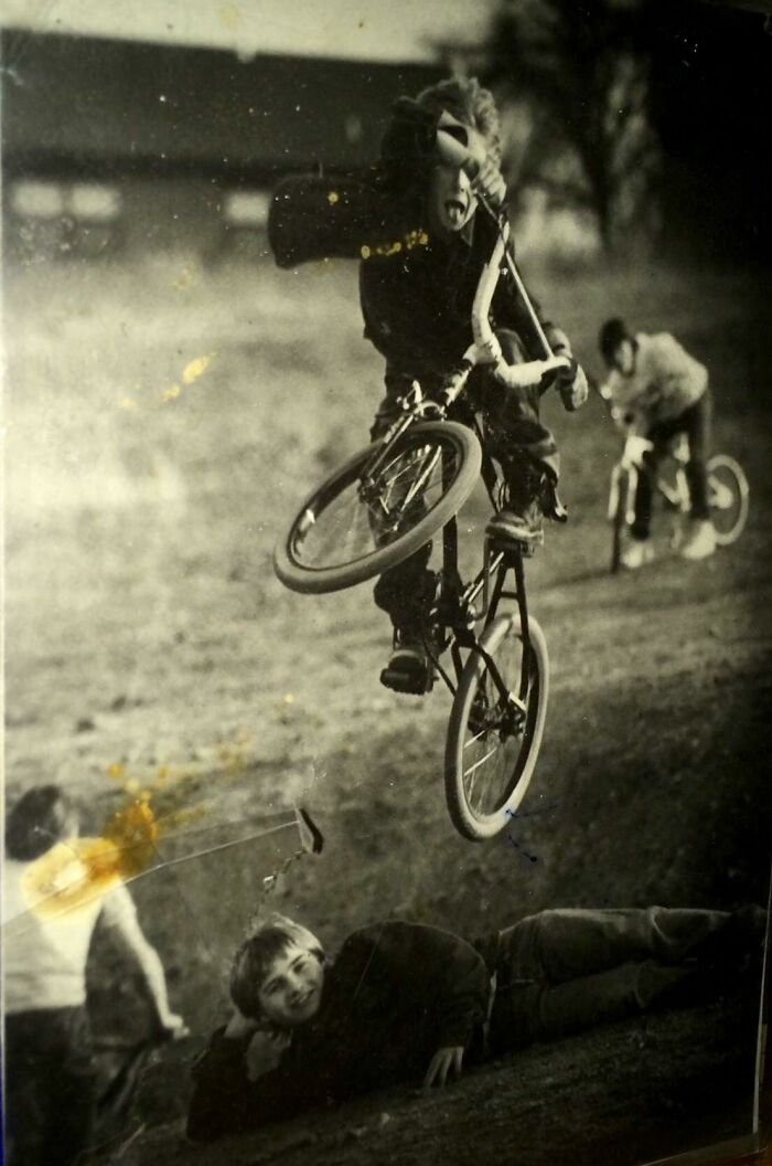 Boy performing BMX stunt over a friend lying on the ground in a wild and wonderful 1980s moment.