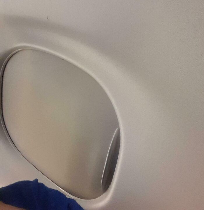 Airplane window with the shade partially open, showing a mildly infuriating thing that tested people's patience.