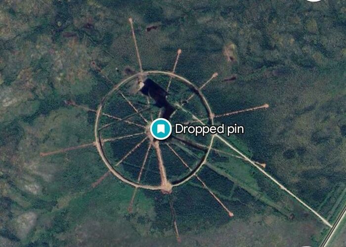 Aerial view of an unusual circular structure in a forested area captured on Google Earth and Maps.