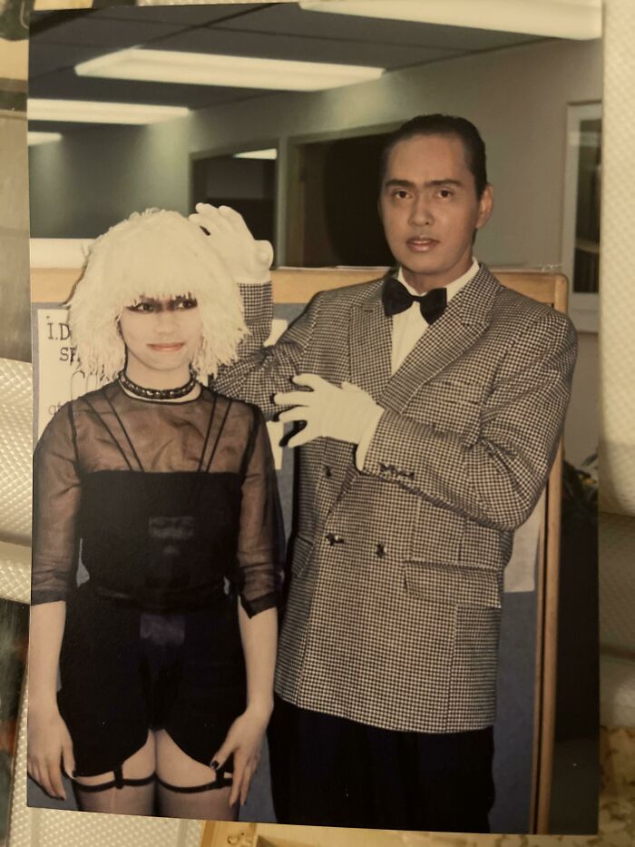 Man in a checkered suit and woman in a black outfit with a white wig, capturing wild and weird 1980s fashion moments.