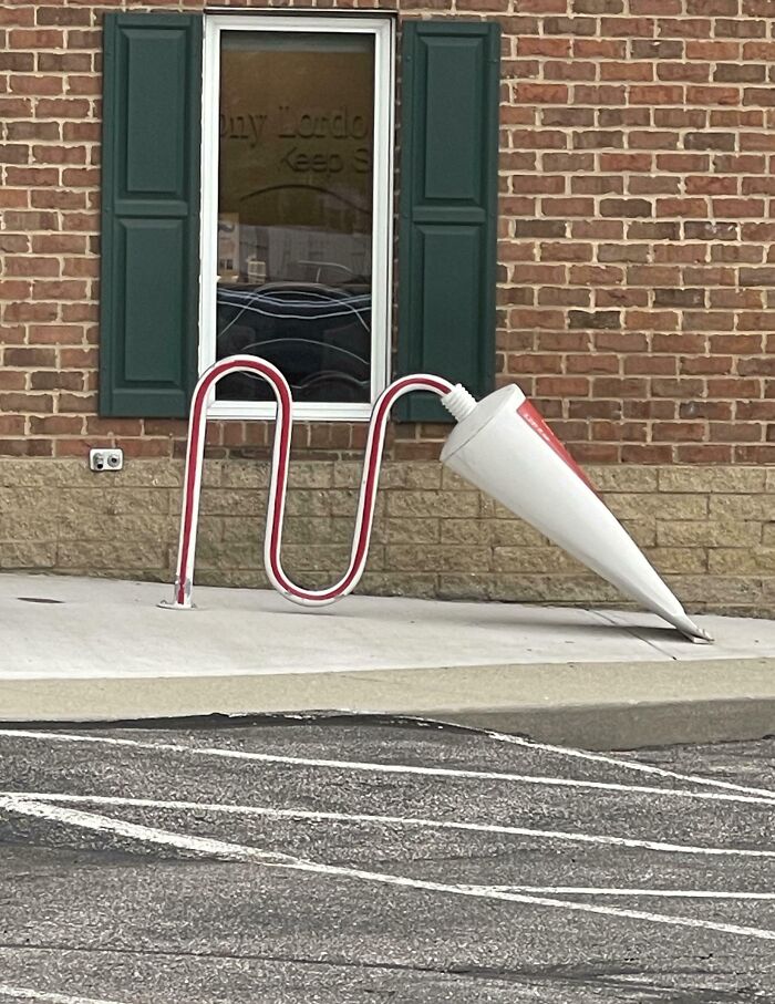 Bike rack shaped like a large tube of ointment outside a brick building showing hilarious and wholesome doctor creativity.