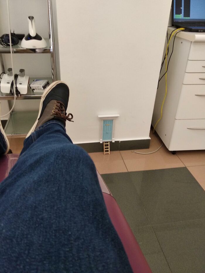 Patient's leg resting in a doctor's office next to a tiny whimsical door and ladder on the wall to ease patients.