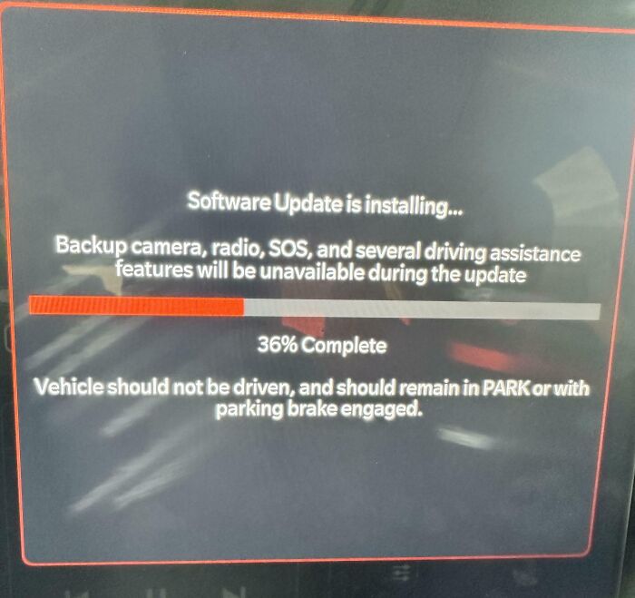 Car software update screen showing 36 percent complete warning of disabled backup camera and driving features.
