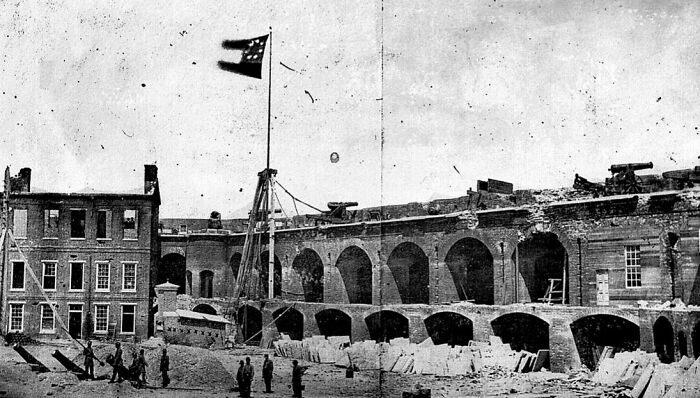 Black and white historical photo showing a damaged fortress with soldiers, from the time when photography was new.