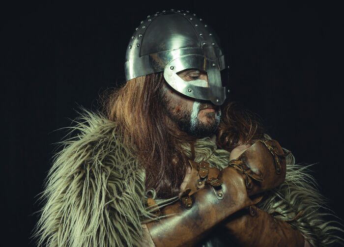 Man dressed as a Viking warrior wearing a metal helmet and fur cloak for 40 interesting and little-known facts about Vikings