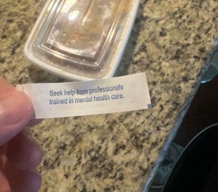 Hand holding a paper slip on a granite countertop with mental health advice related to psychology memes.