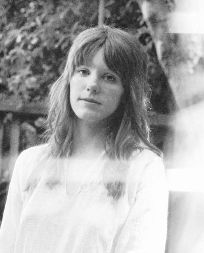 Young woman in a white shirt looking thoughtfully, representing people who left a mark in movie and music industries.