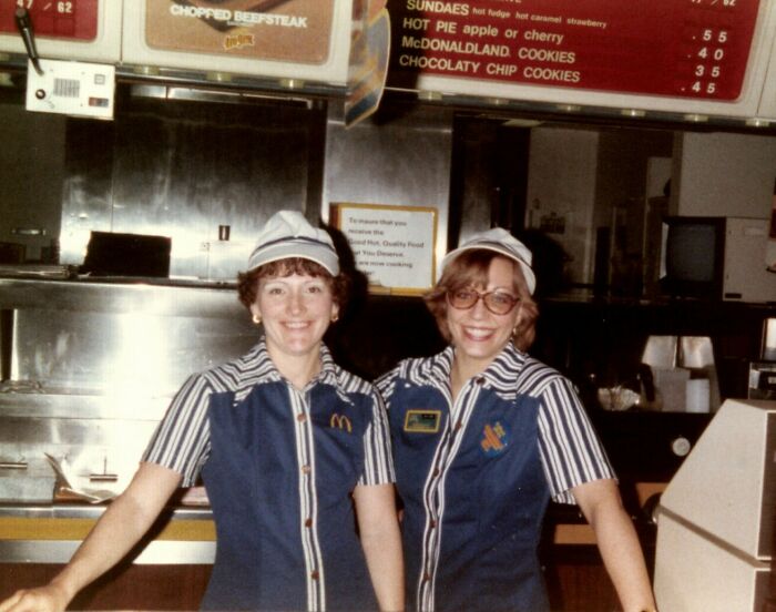 Two smiling McDonald's employees in 1980s uniforms behind the counter showcasing wild 1980s fast food fashion.