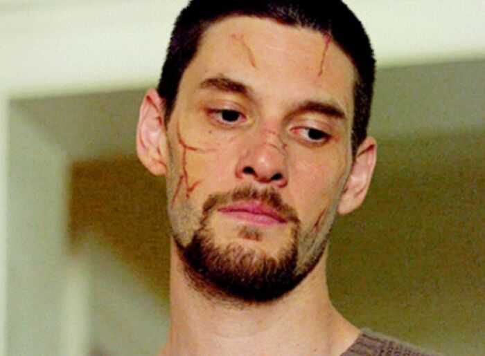 Man with facial scars looking down, featured in a collection of bad movie details and confusing scenes.