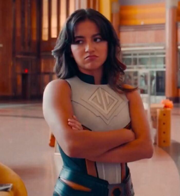 Young woman in futuristic outfit with arms crossed, showing a confused expression about bad movie details in an online group.