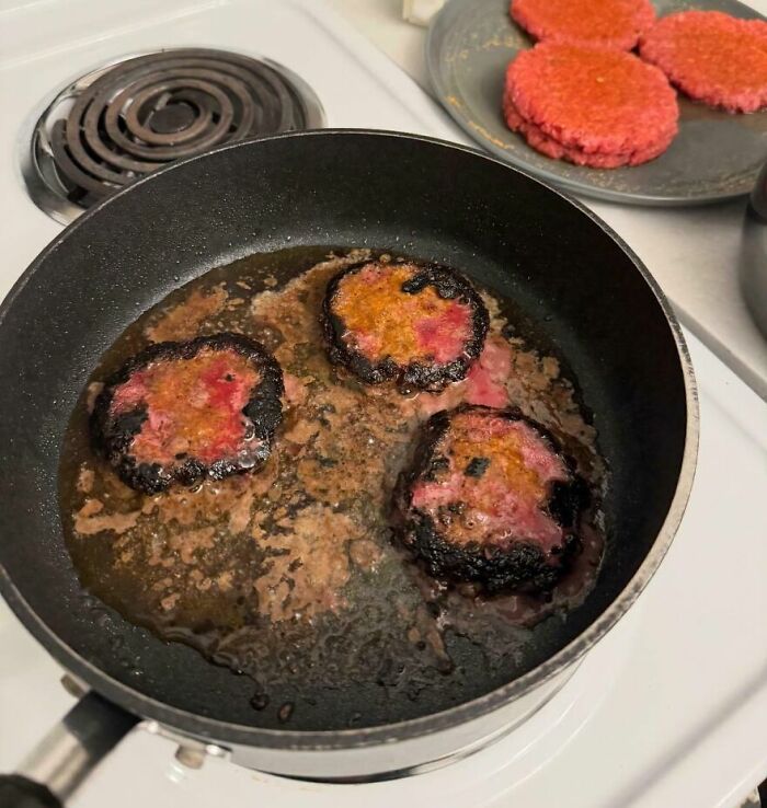 Burnt and greasy food frying in a pan with raw patties on a plate, showing cursed and disgusting pictures of food.