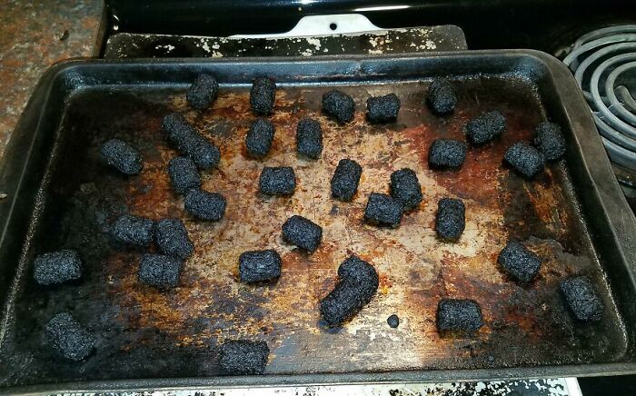 Burnt and cursed food pieces on a heavily stained baking tray, showcasing disgusting food that might make you go eeeeew.