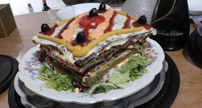 Layered savory dish with odd sauces and olives on lettuce, one of the cursed and disgusting pictures of food.