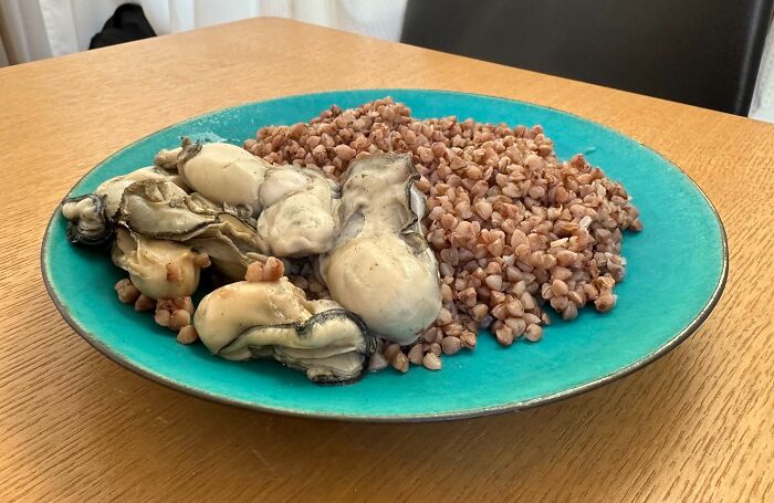 Plate of cooked buckwheat and slimy oysters on a blue dish, showing a cursed and disgusting food combination.