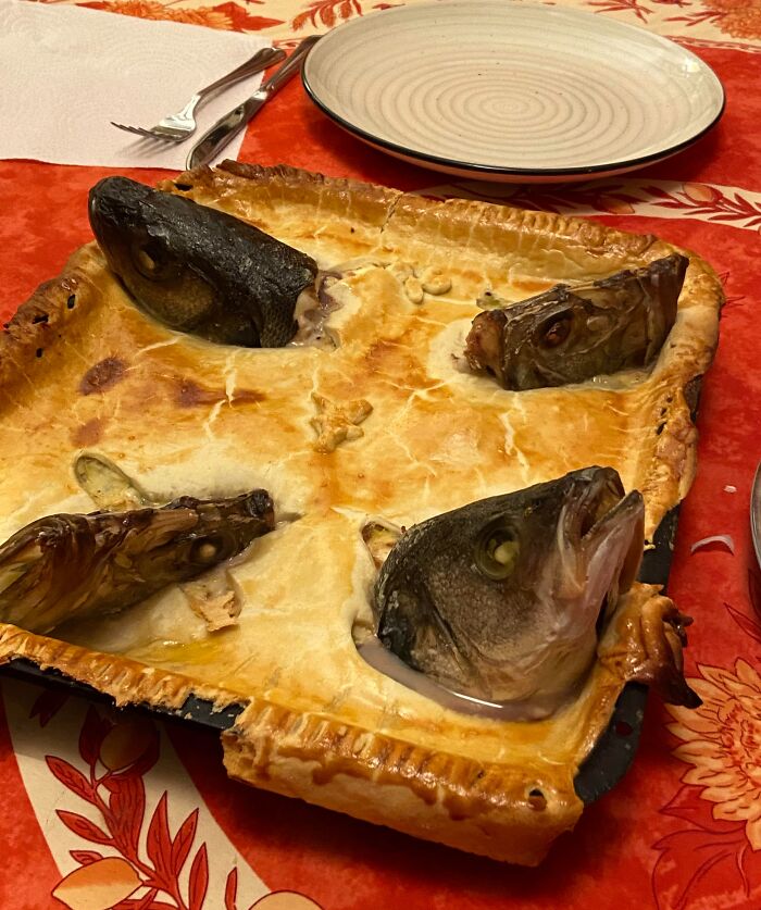 Baked pie with four fish heads emerging from the crust, an example of cursed and disgusting pictures of food.