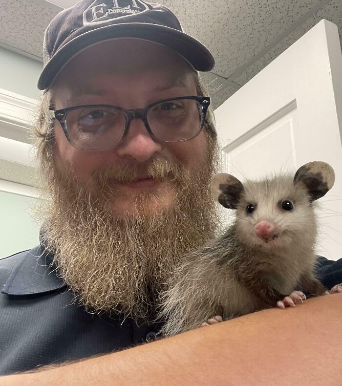 Man with glasses and hat holding a cute baby animal, showcasing adorable baby animal pics that evoke aww reactions.