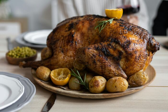 Roasted turkey with potatoes and lemon on a wooden plate, illustrating workplace rules that annoyed everyone.