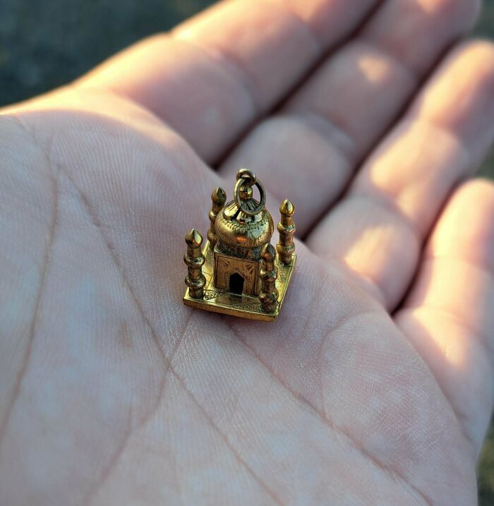 A small gold temple charm held in hand, one of the lucky thrift store shoppers hitting the jackpot finds.