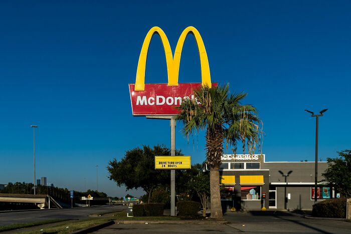 McDonald's restaurant exterior with a visible drive-thru sign highlighting workplace rules and regulations.