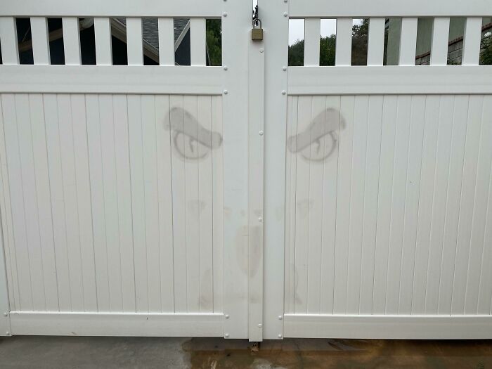 White gate with faded spooky face stains resembling Halloween fails on the surface, dampening the festive mood.