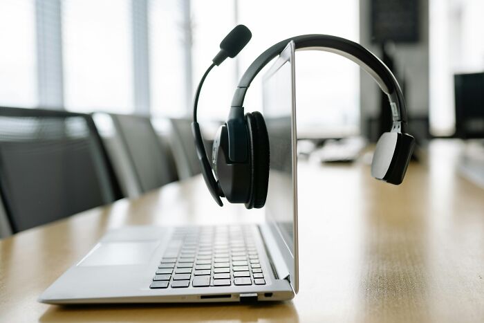 Laptop with headset on a conference table in an office, illustrating workplace rules and office headset use.
