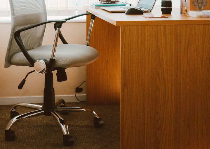 Office chair and wooden desk in a workspace illustrating strict workplace rules that annoyed employees and created tension.